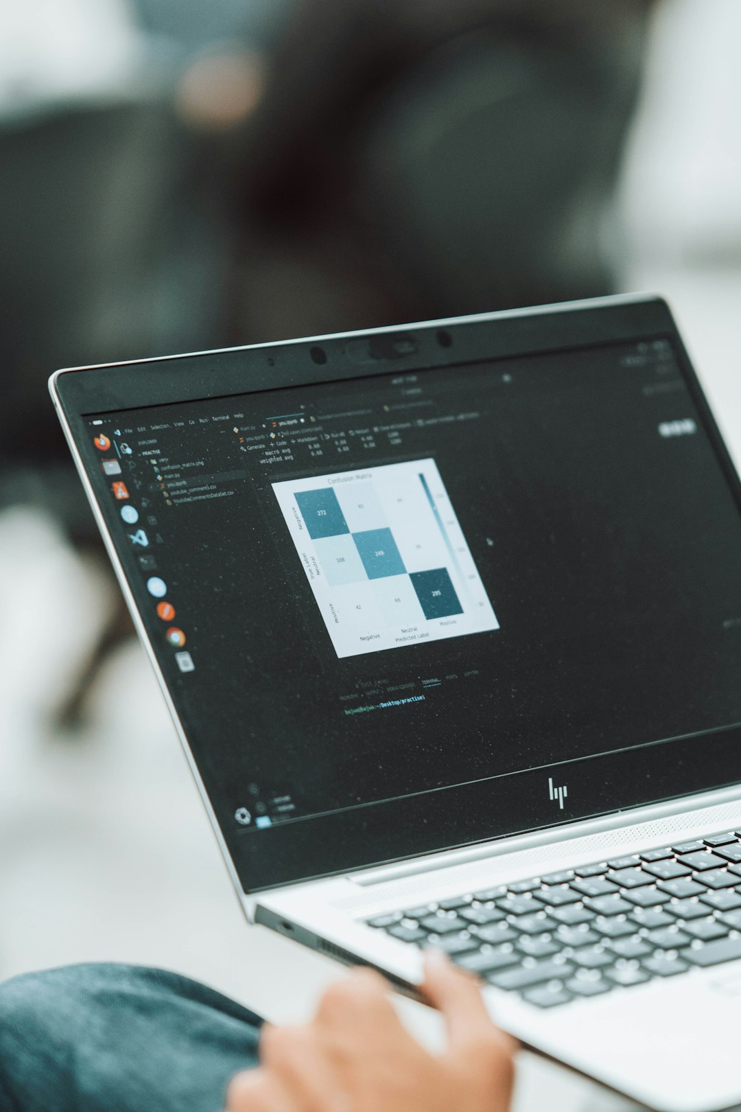 A focused university student working on a laptop in a quiet library space, surrounded by bookshelves. Natural light adds a calm academic vibe.